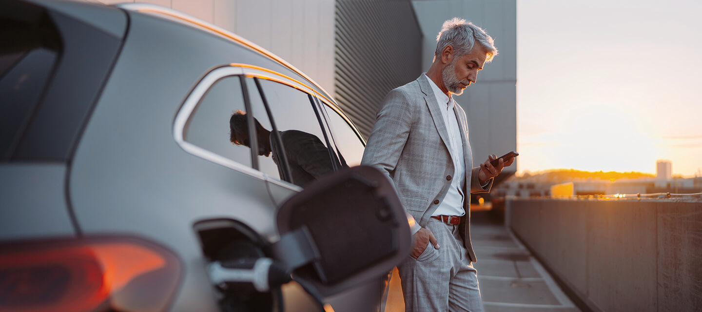 A man looking at his phone while his electric car charges