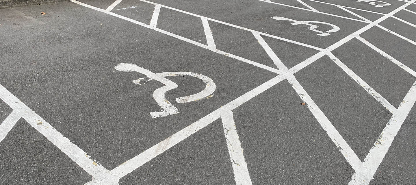A row of disabled parking bays in a public car park, painted with white paint