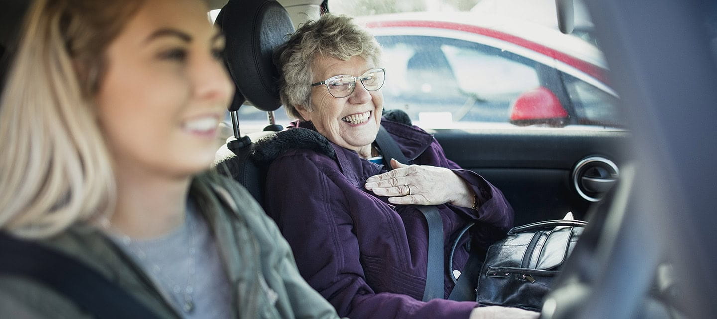 Young woman driving with her Grandmother sitting in the passenger seat.