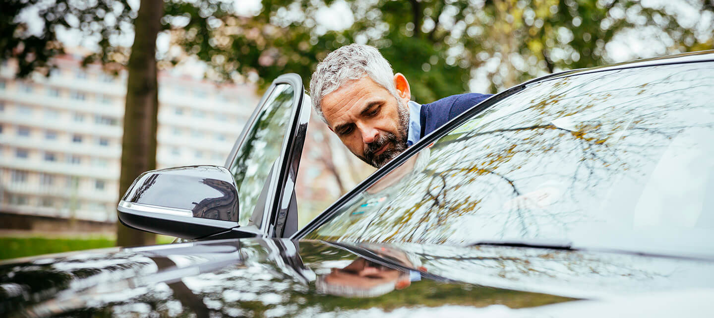 A mature man getting into his luxury car