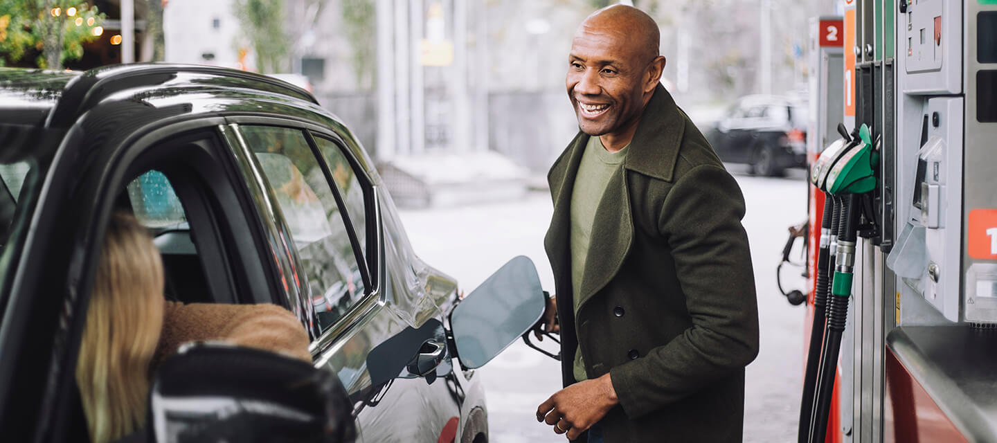 A mature man talking to a woman while refuelling car while at petrol station