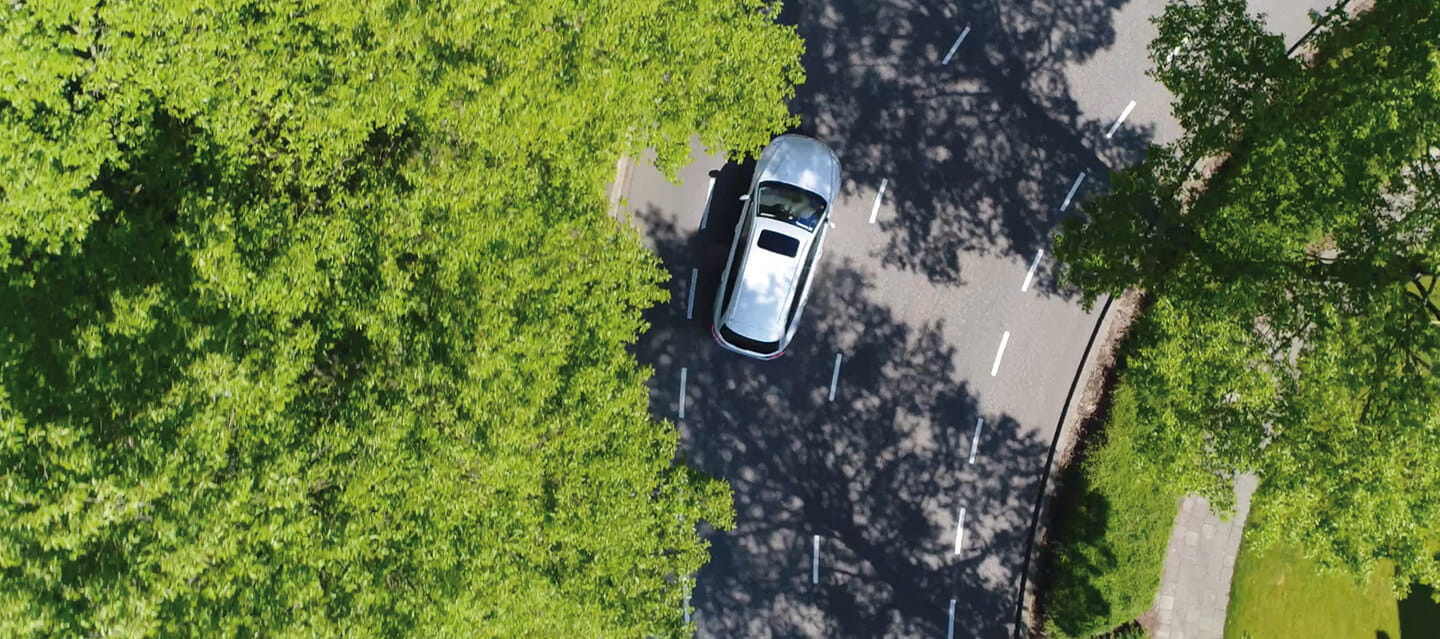 Aerial view of a car driving in a leafy suburb