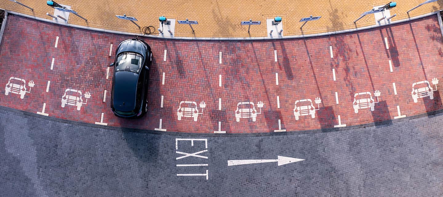 An aerial view directly above an electric vehicle charging station with electric car charging in a parking space