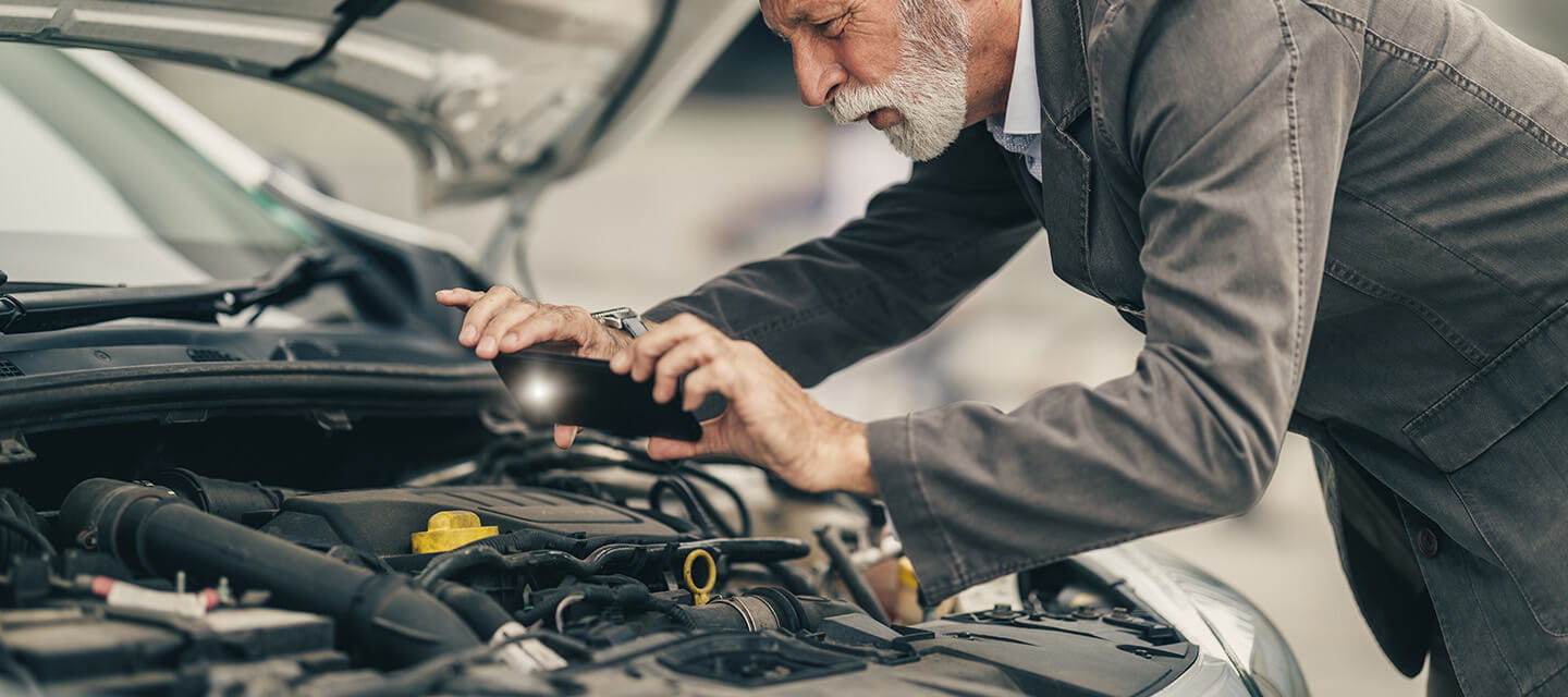A mature man looking under the bonnet of a used car