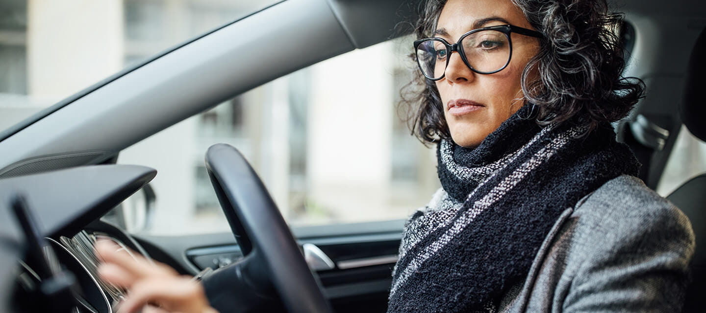 A mature woman dressed for cold weather driving in her car