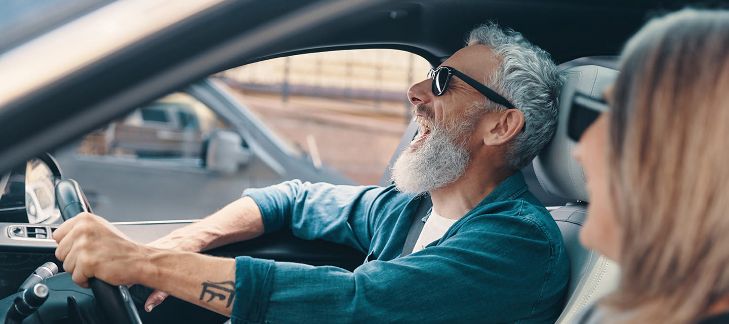 A senior couple laughing at a joke while driving 