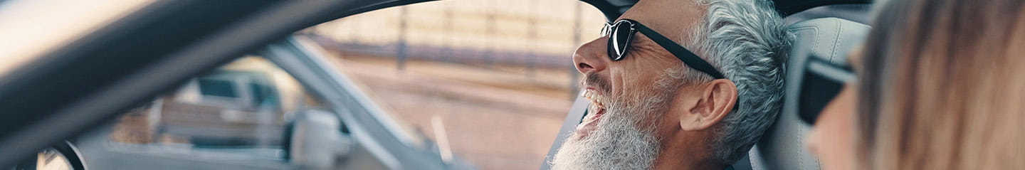 A senior couple laughing at a joke while driving 