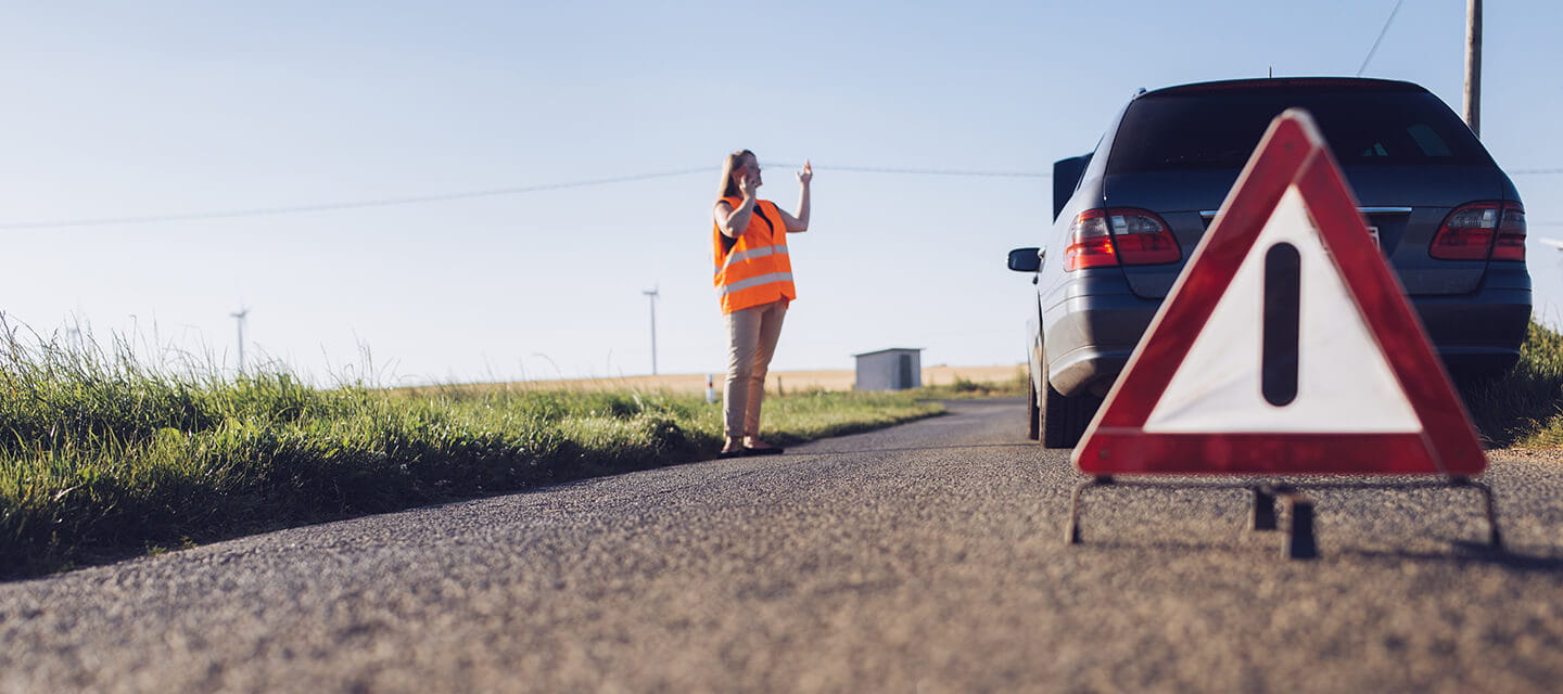 Long blondhaired woman have car breakdown in a rural landscape.