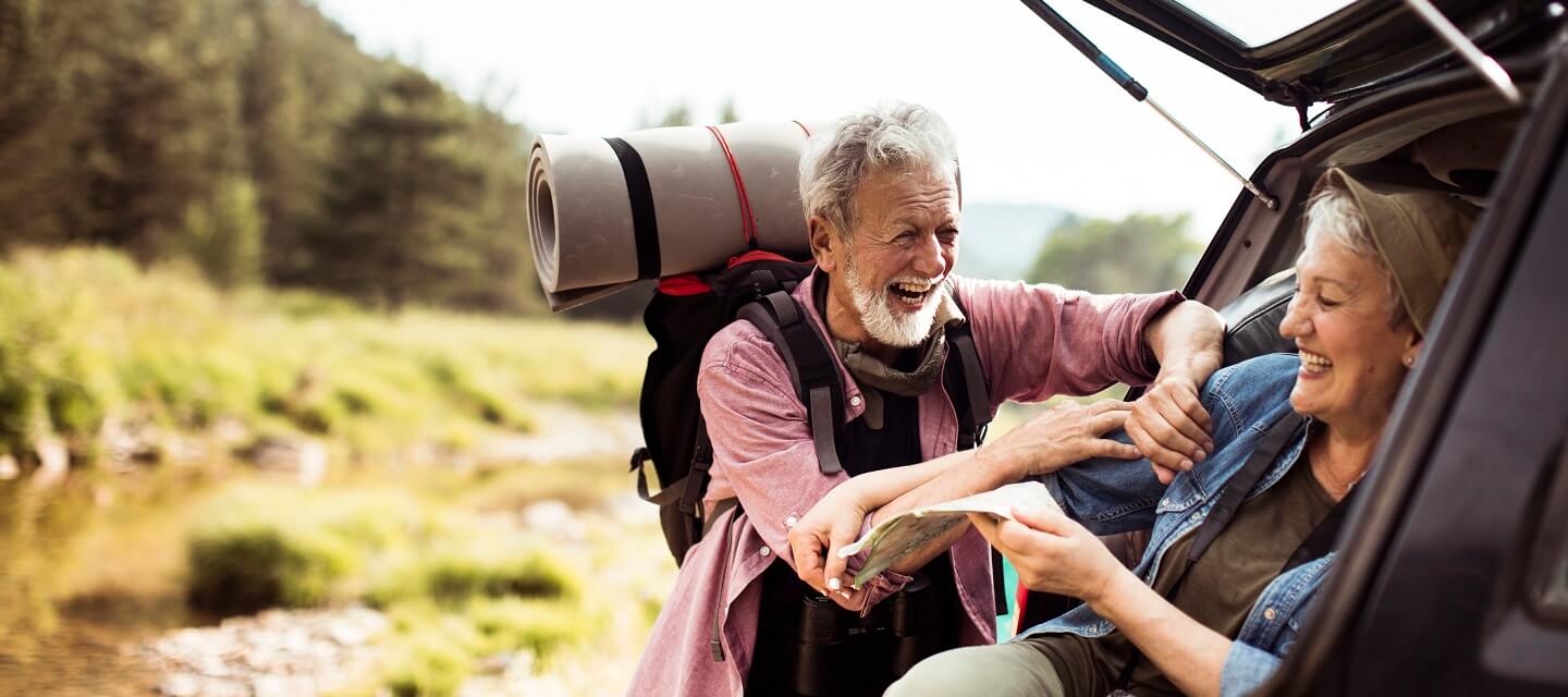 A happy couple getting ready to go hiking at the boot of their car