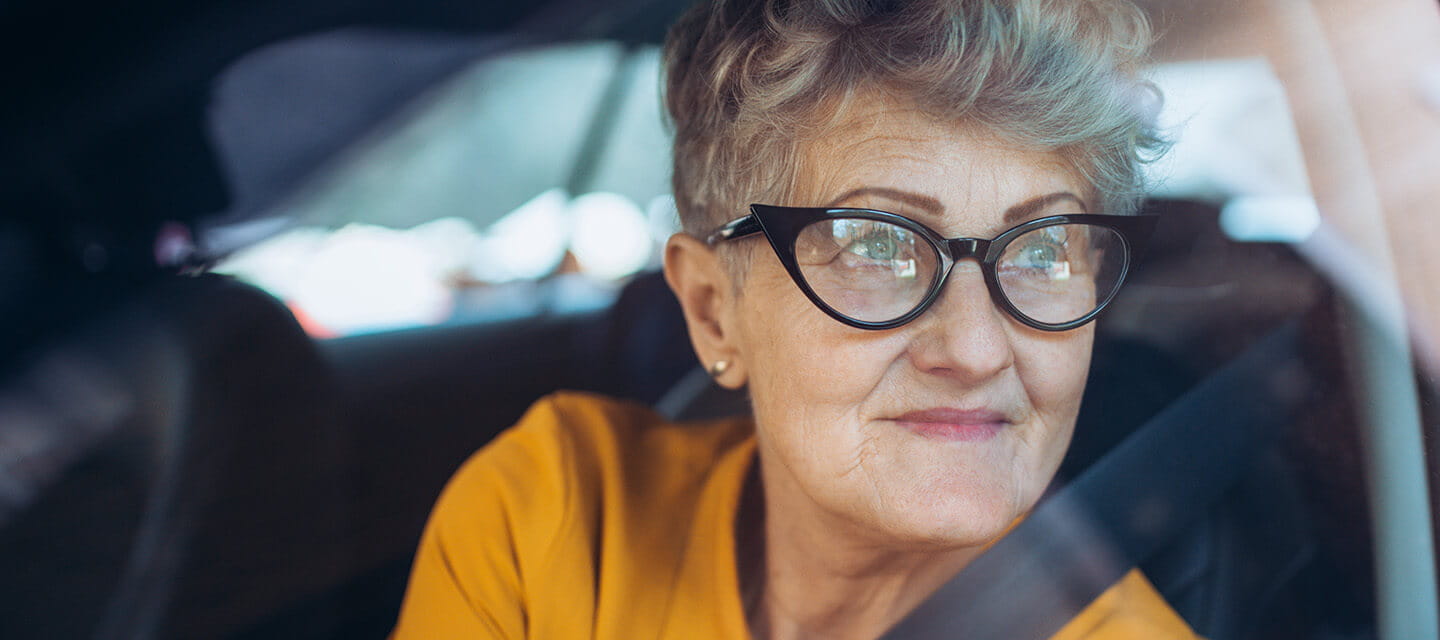 An elegant mature lady gazing longingly out of her car window