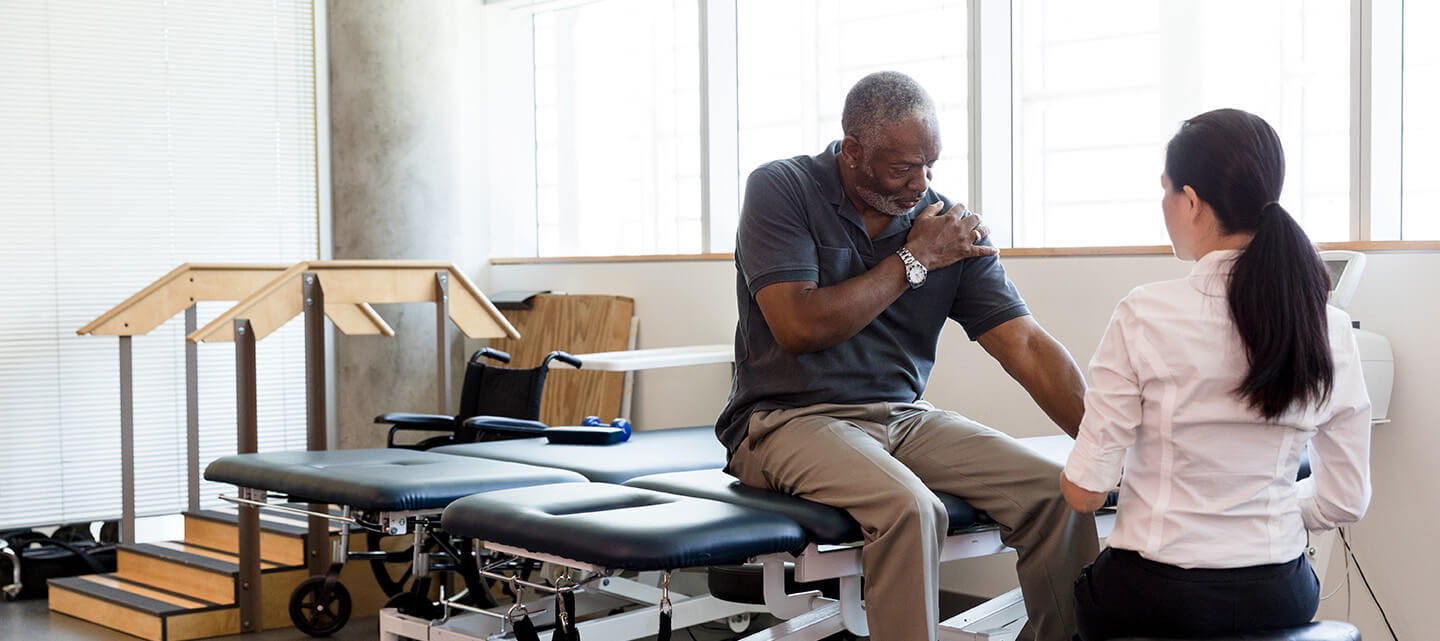 Senior man with an injured shoulder in rehab clinic