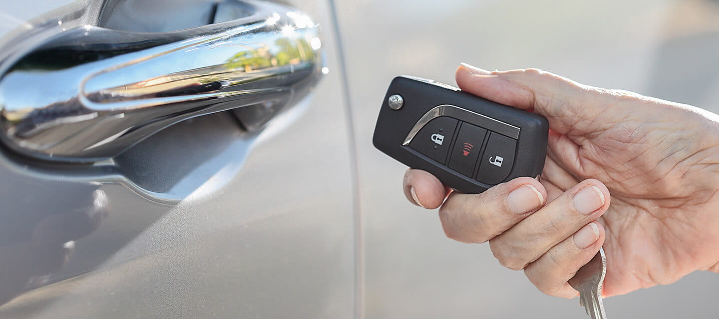 Close up of a woman's hand holding a car key next to the car door