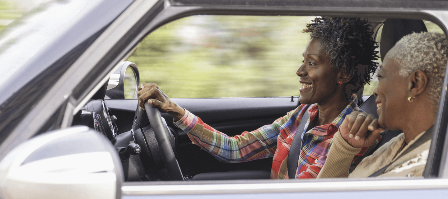 Two smiling women driving with the window down