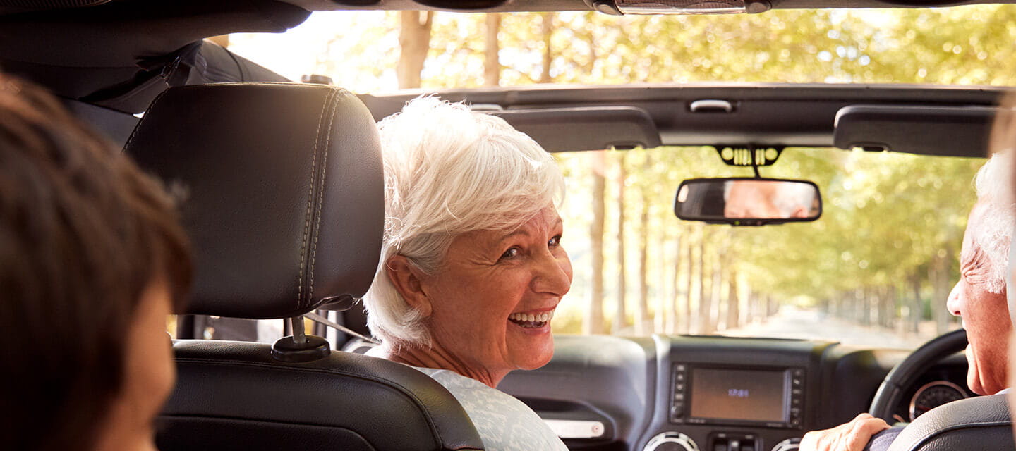 A happy couple enjoying a drive with their grandchildren