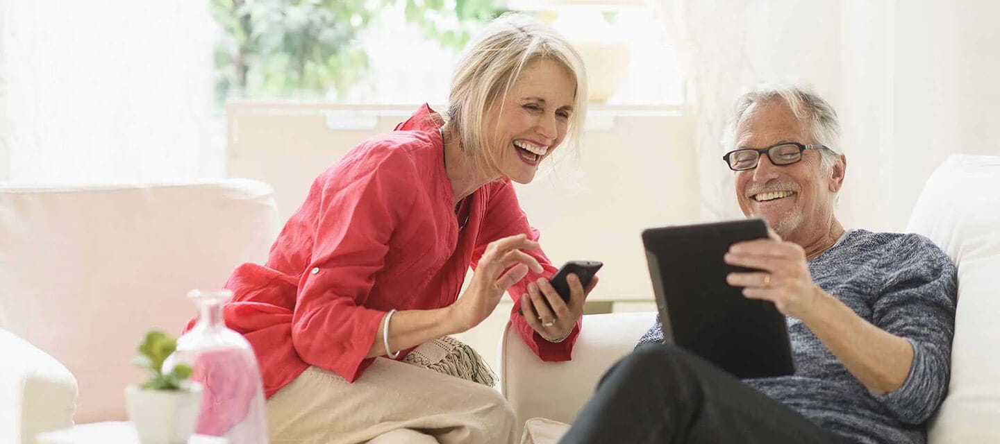 A mature couple smiling while looking at a tablet computer