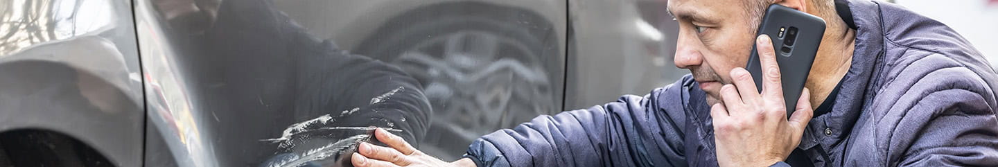 A man calls his insurance company because someone backed into the side door of his car in a car park.