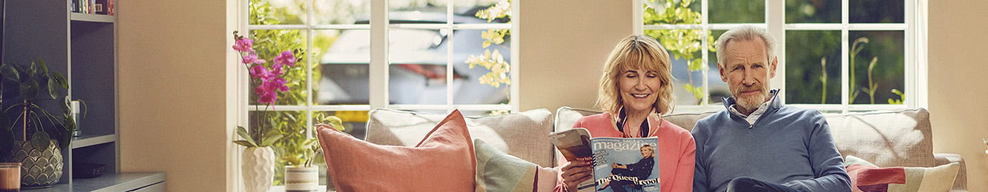 A happy mature couple sat together in their living room on a sunny morning
