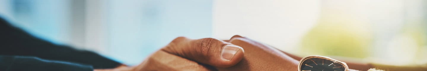 Two pairs of hands holding each other across a table