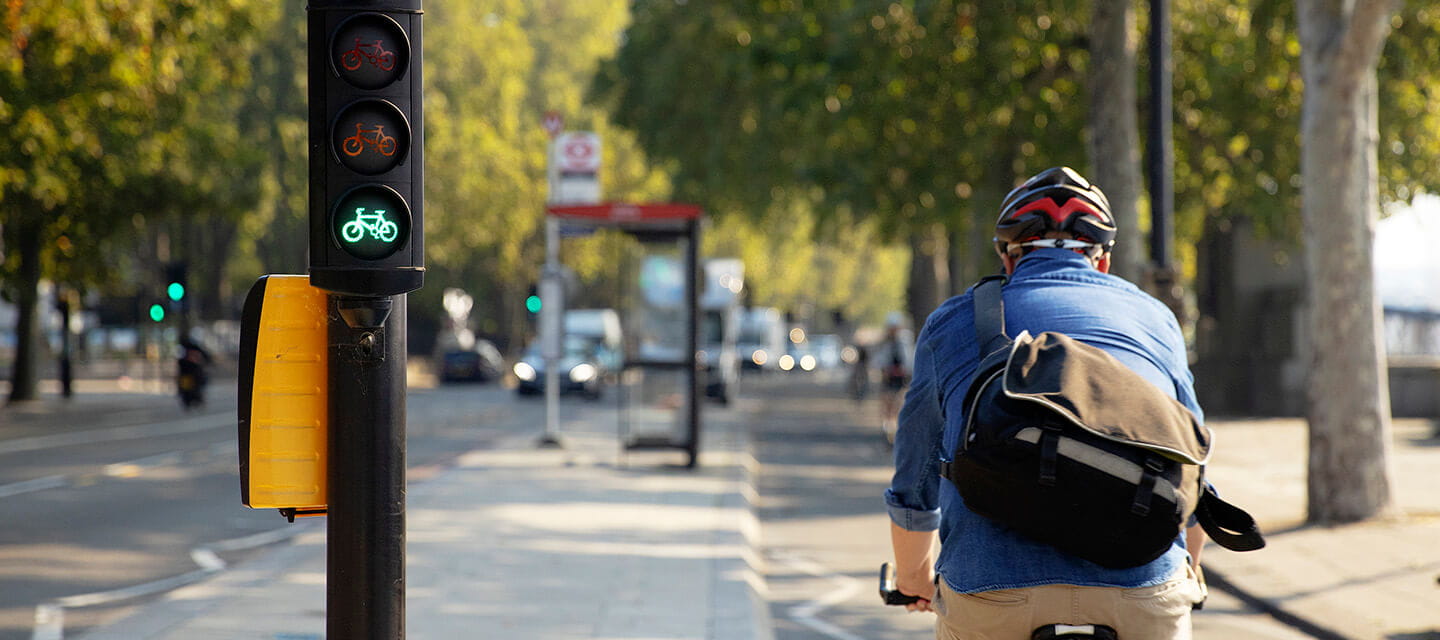 Senior man cycling away from camera in bike lane on the Embankment London