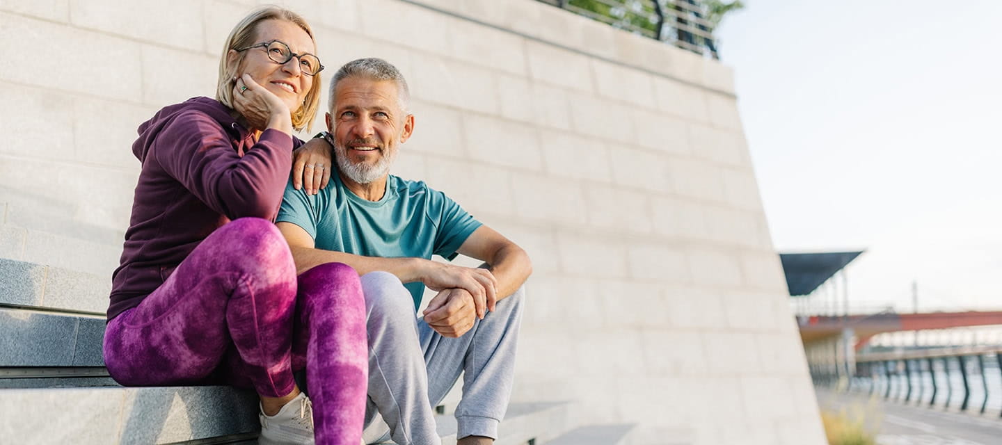 Active mature couple sharing quality time sitting on steps outside.