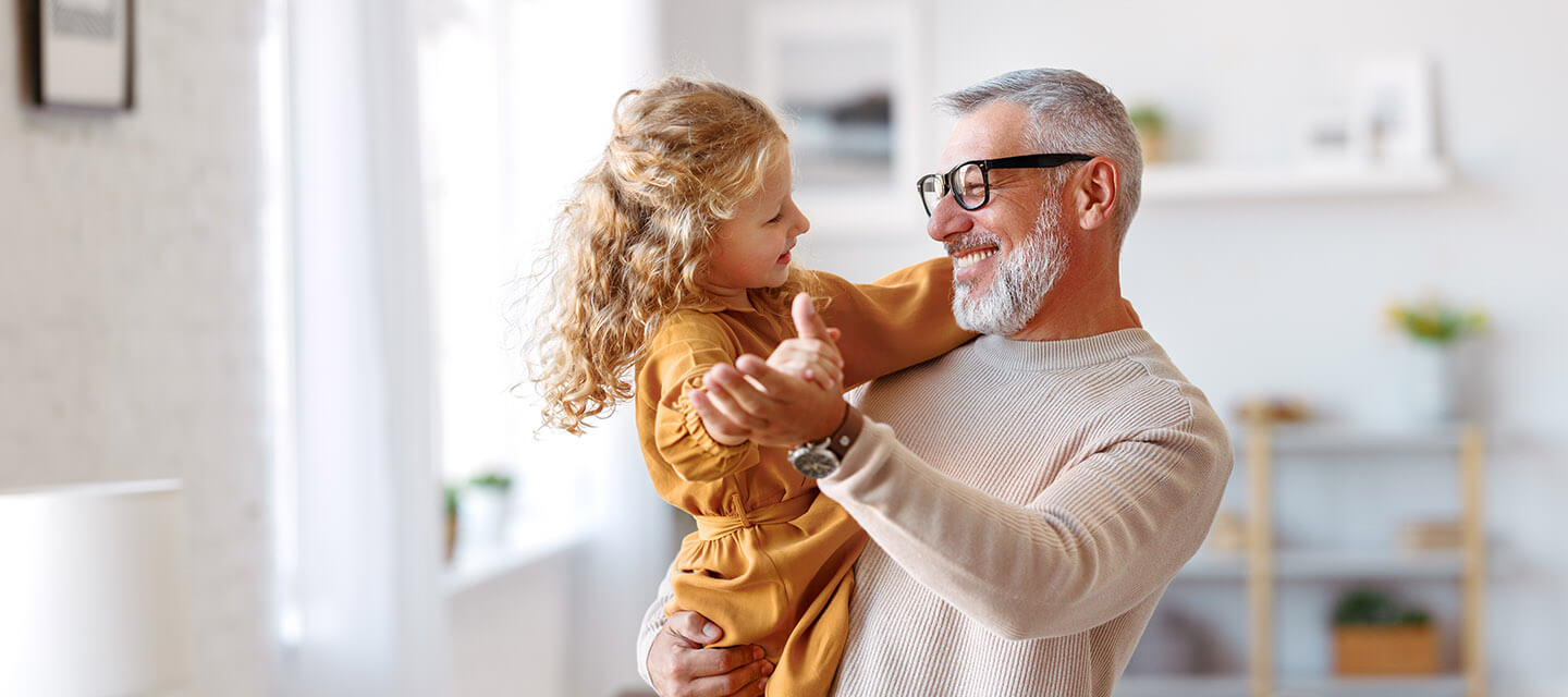A smiling man holding his granddaughter