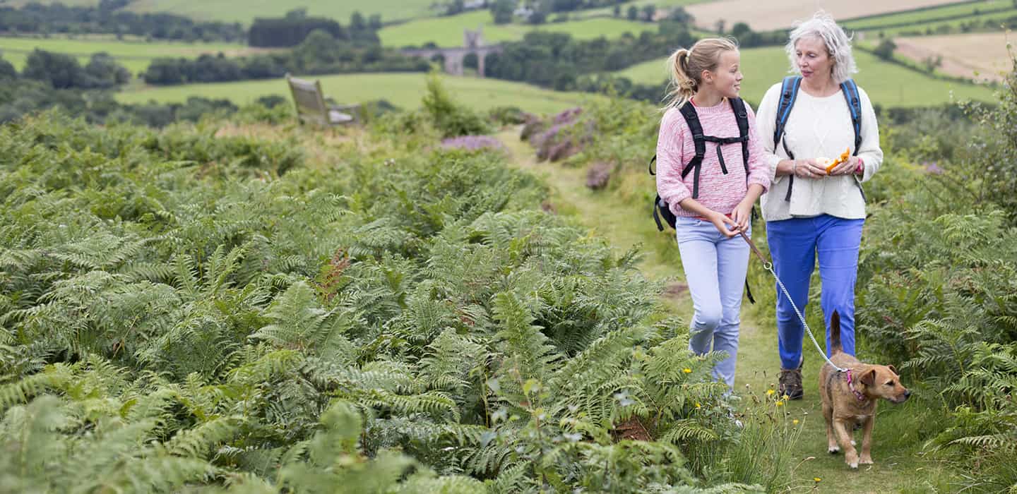 A woman walking her dog in the countryside with her granddaughter  