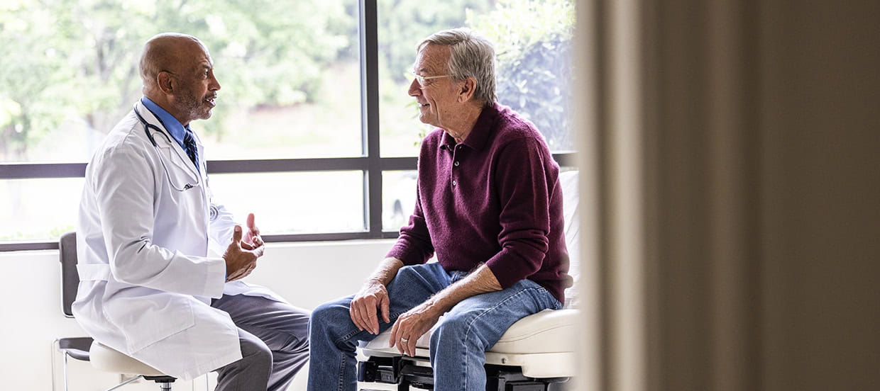 Male doctor talking with senior man in a private examination room.