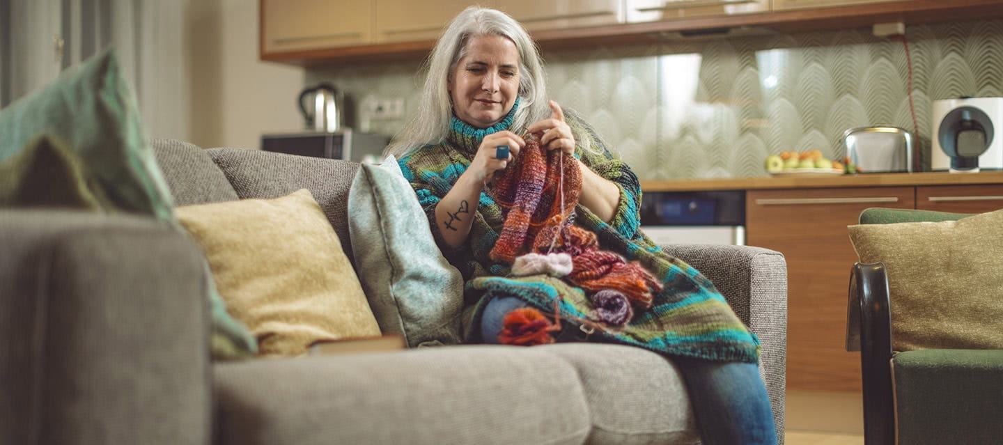 Mature woman is relaxing and knitting at home