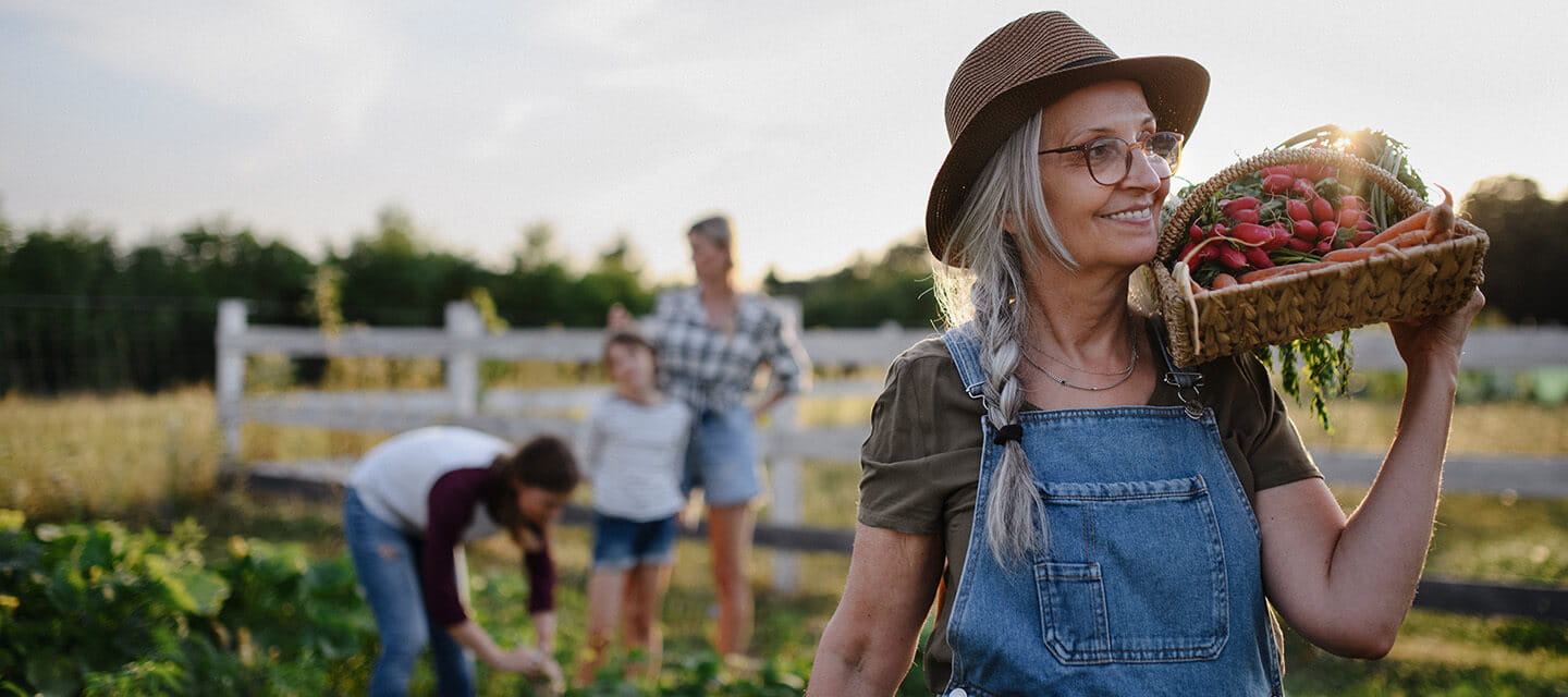 Mature woman carrying basket with homegrown vegetables outdoors