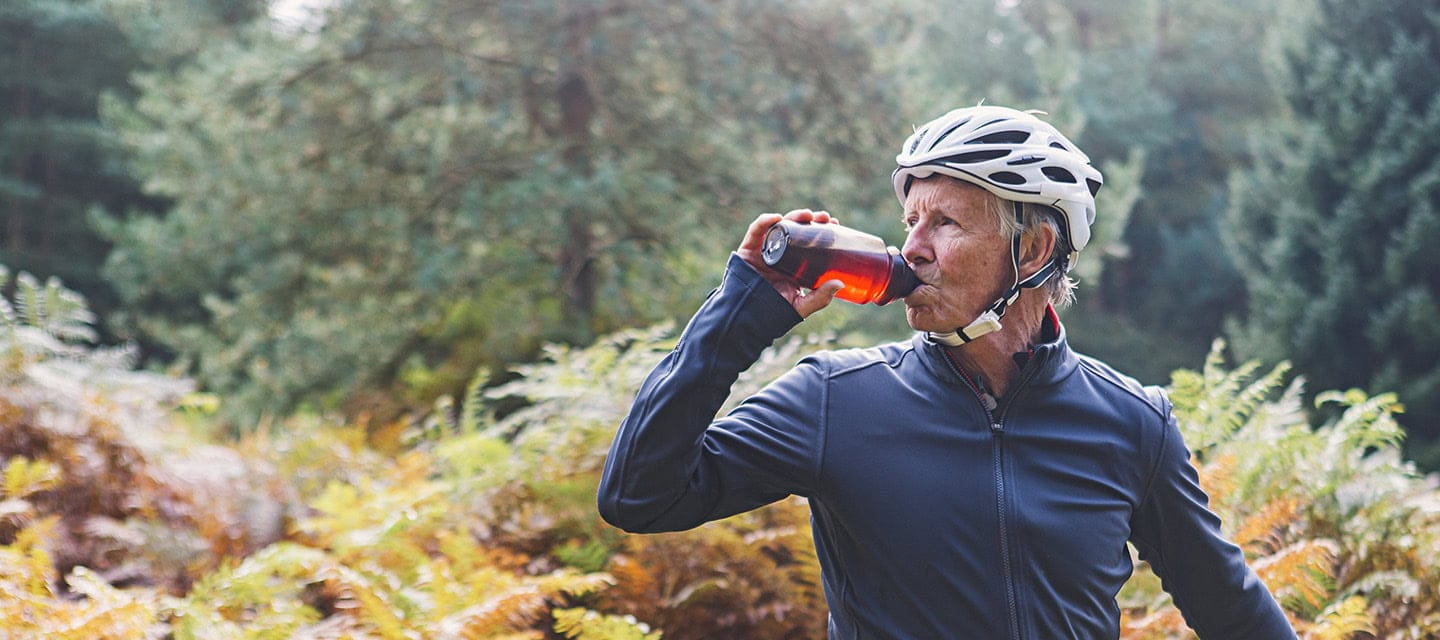 A mature cyclist taking a drinks break in an autumnal forest