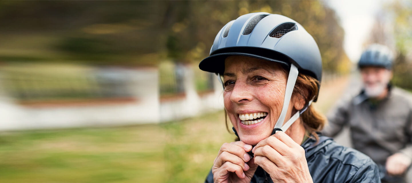 An active mature woman smiling while wearing a bike helmet