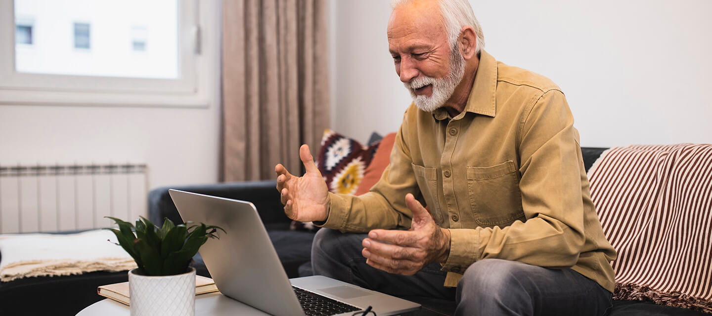 A mature man talking on a video call via his laptop