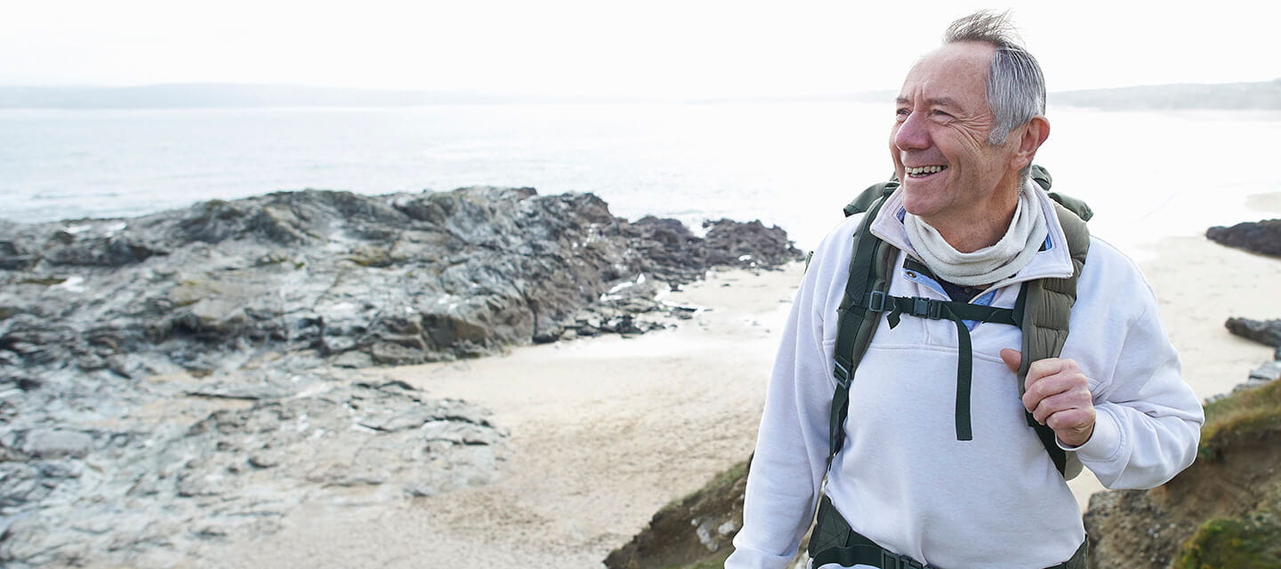 Happy senior man hiking along coastline