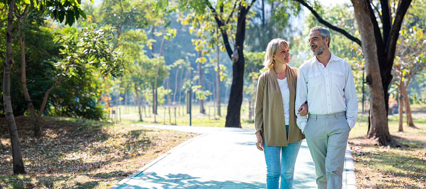 Senior couple taking a walk in a park during a summer morning.