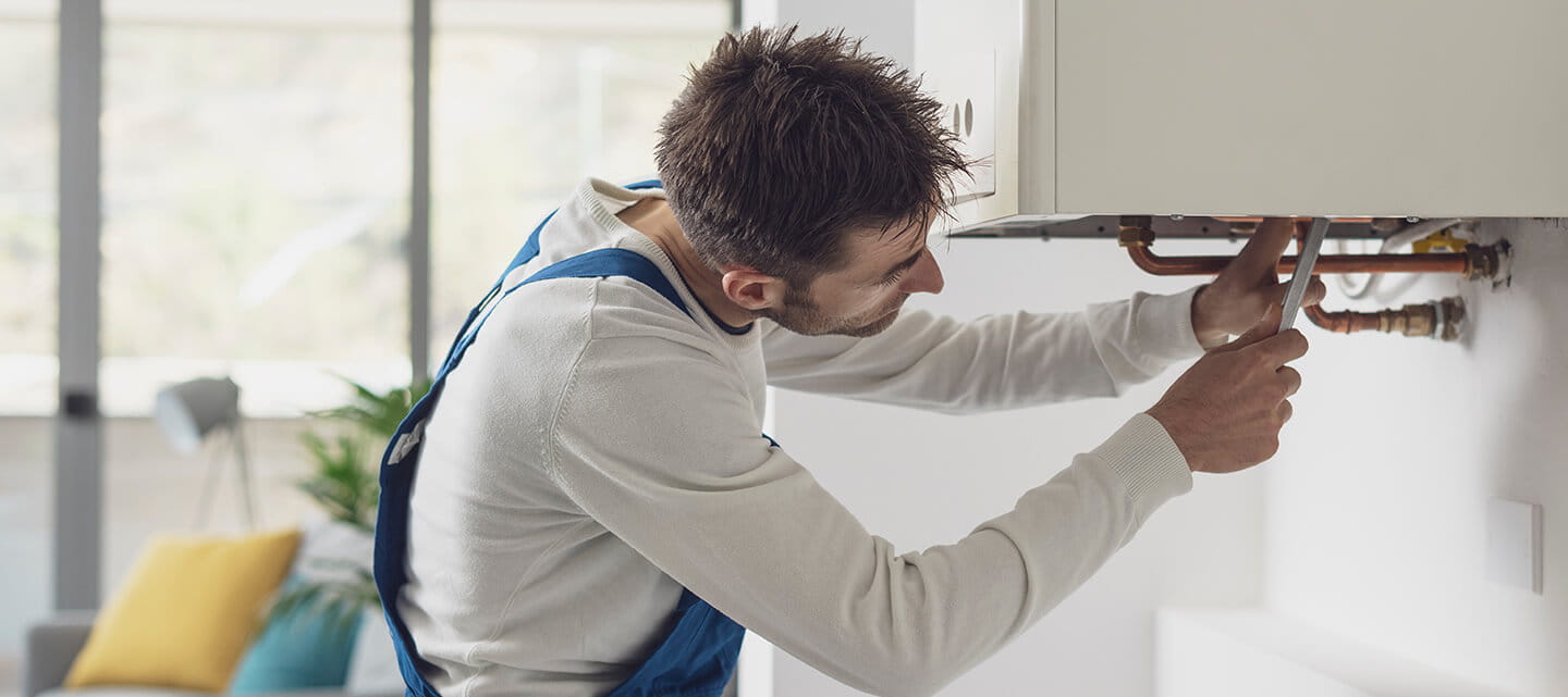 A plumber servicing a home boiler