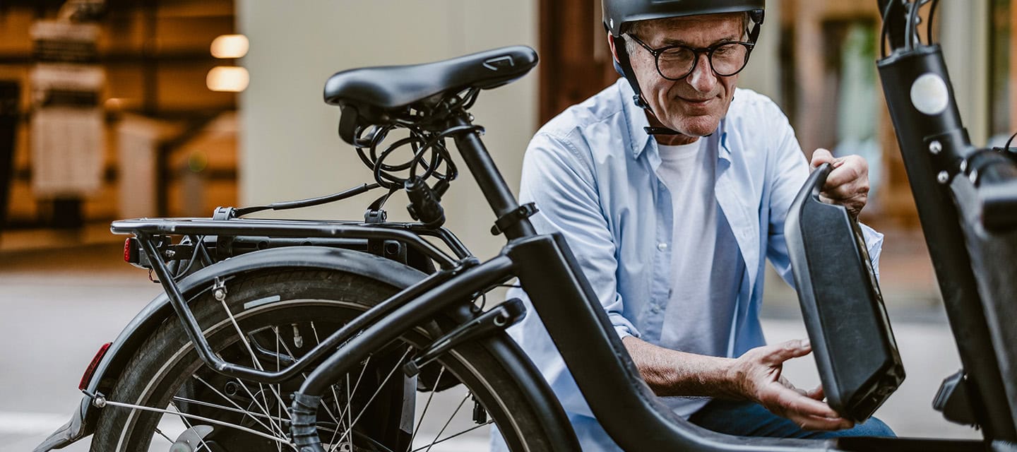 Senior man changing battery on electric bicycle
