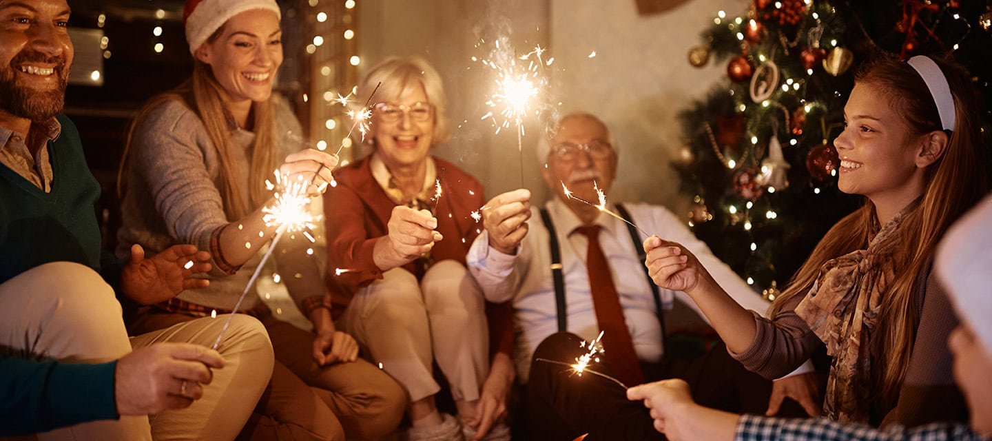 Cheerful extended family having fun with sparklers while celebrating Christmas together at home.