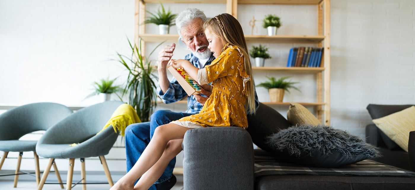 A man with his Granddaughter looking at an abacus