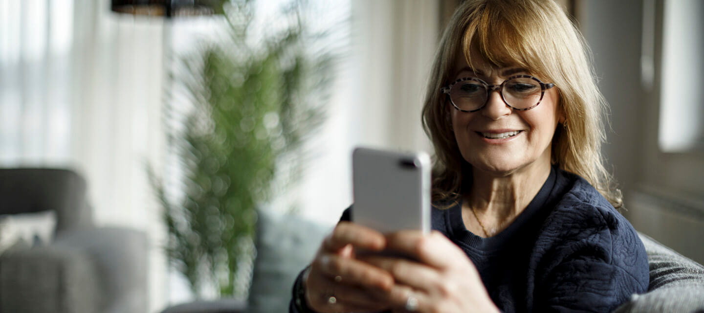 A mature lady sat at home looking at her mobile phone