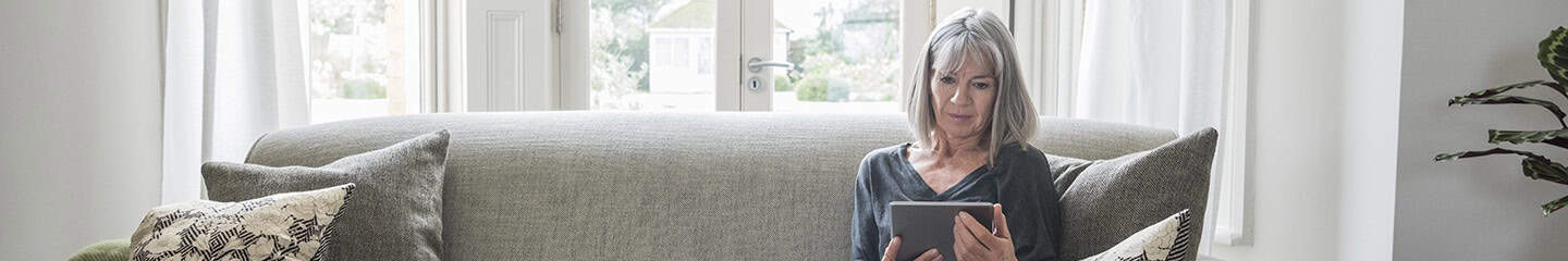 Senior woman sitting relaxing on the sofa using digital tablet 
