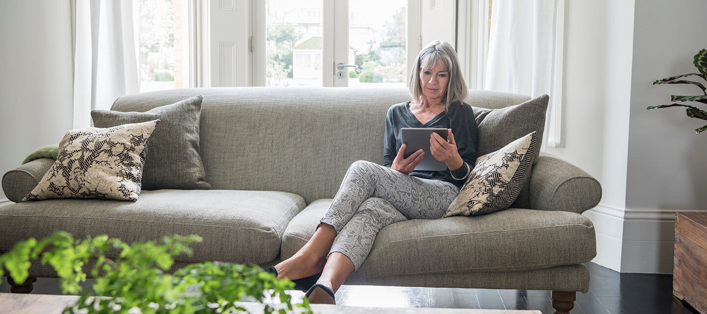 Senior woman sitting relaxing on the sofa using digital tablet 