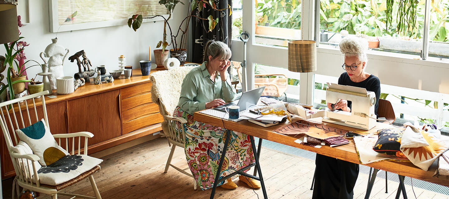 Two craft enthusiasts working at dining room table