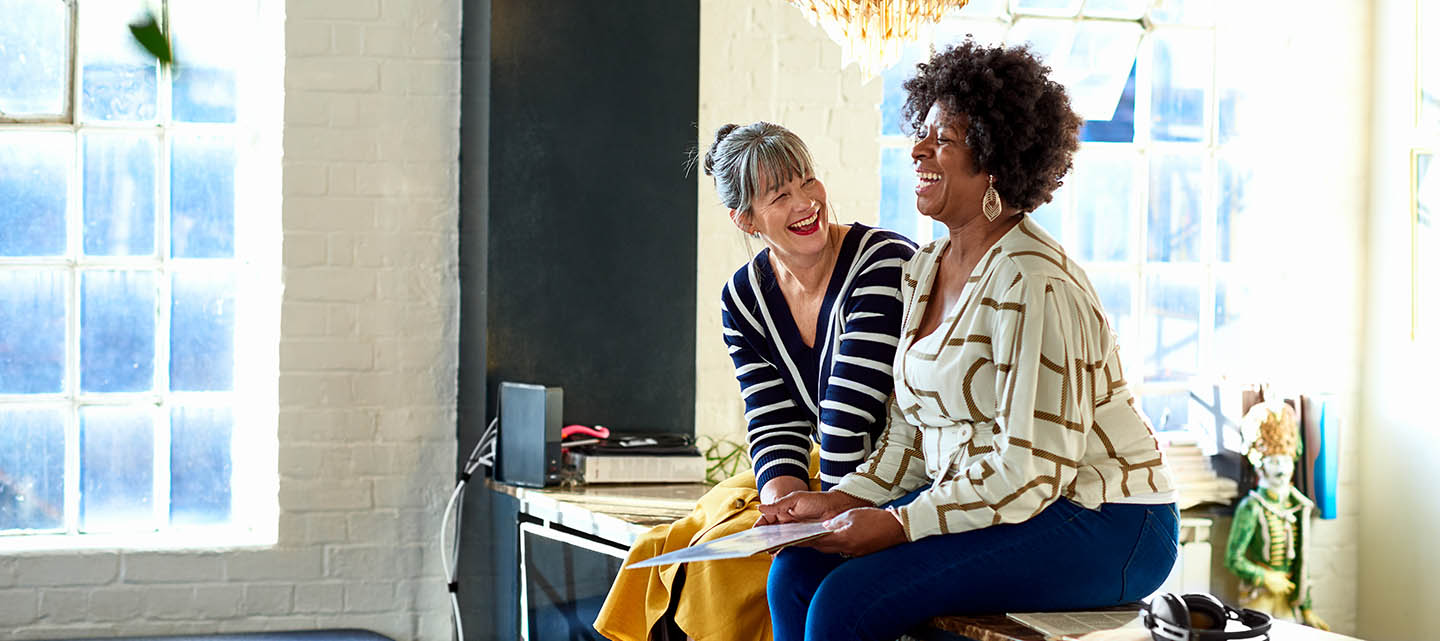 Two women sat on a counter laughing while listening to records