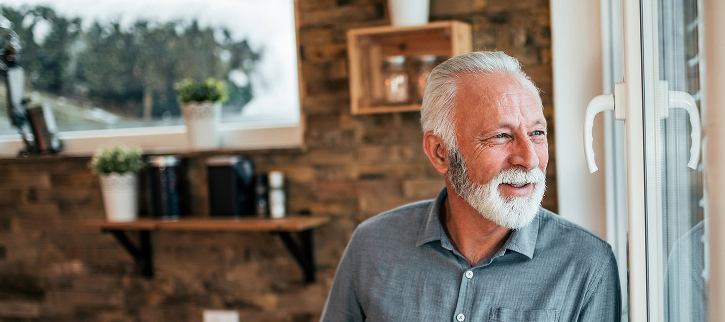 A man looking out of his kitchen window enjoying a coffee