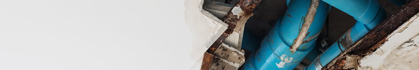 A hole in a ceiling exposing pipework