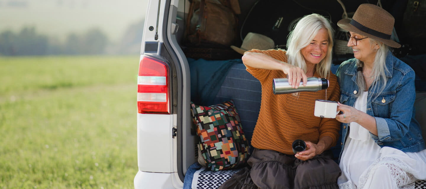 Two women sat drinking coffee on the back of their motorhome