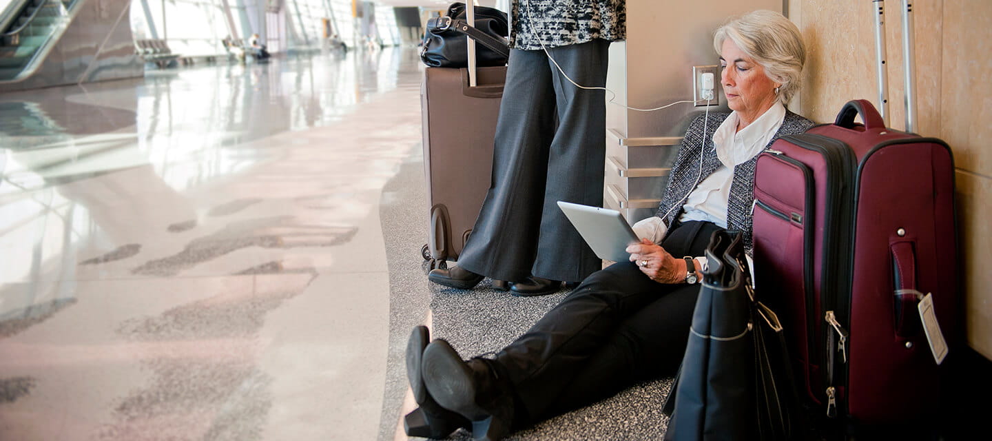 Businesswomen at an airport between flights using a plug socket to charge their devices