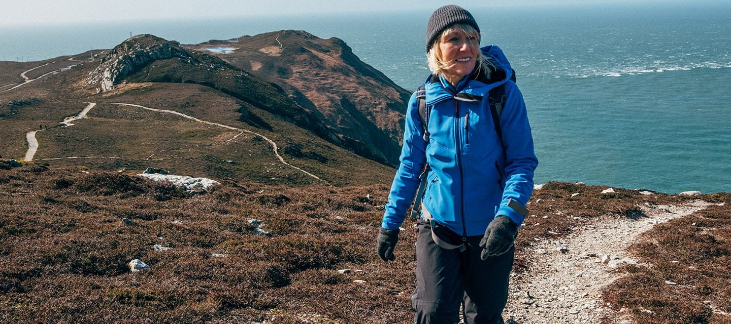 Senior woman hiking on Holyhead Mountain on the island of Anglesey, North Wales, UK.