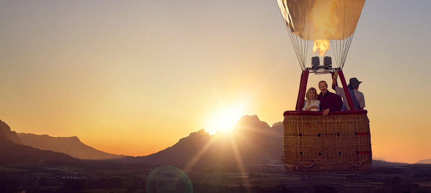 A mature couple enjoying a hot air balloon ride as the sun sets over South Africa.