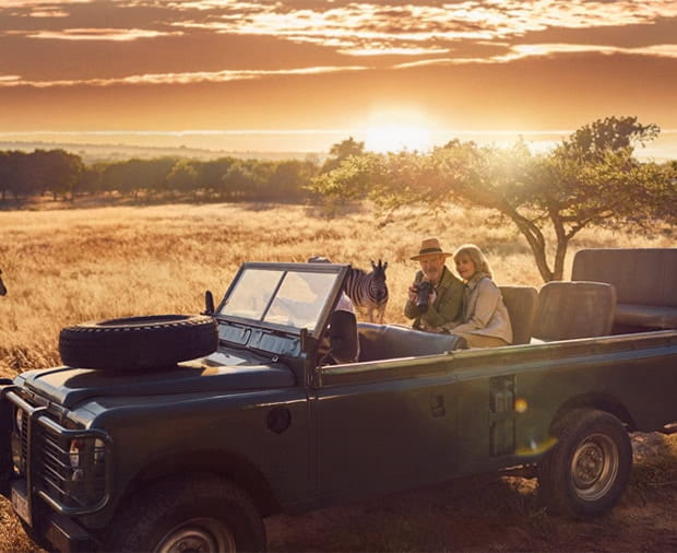 A couple out on safari, being watched by a zebra.